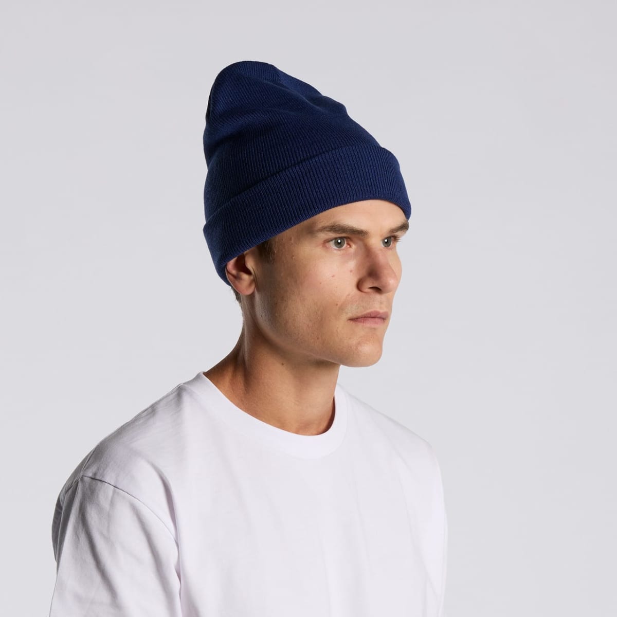 Person in a blue beanie and white t-shirt looking to the side against a light background.