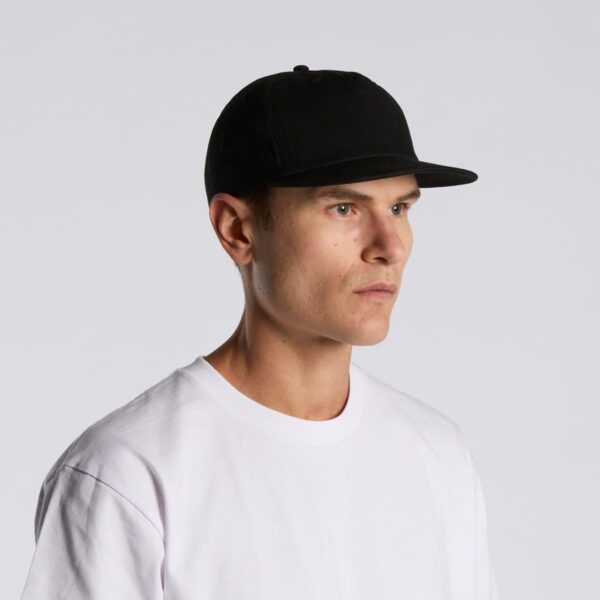 Man in a black cap and white t-shirt looking to the side against a plain background.
