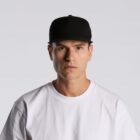 Man in a black cap and white shirt looking straight at the camera with a neutral expression.