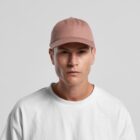 Man wearing a pink cap and white t-shirt against a plain light gray background.