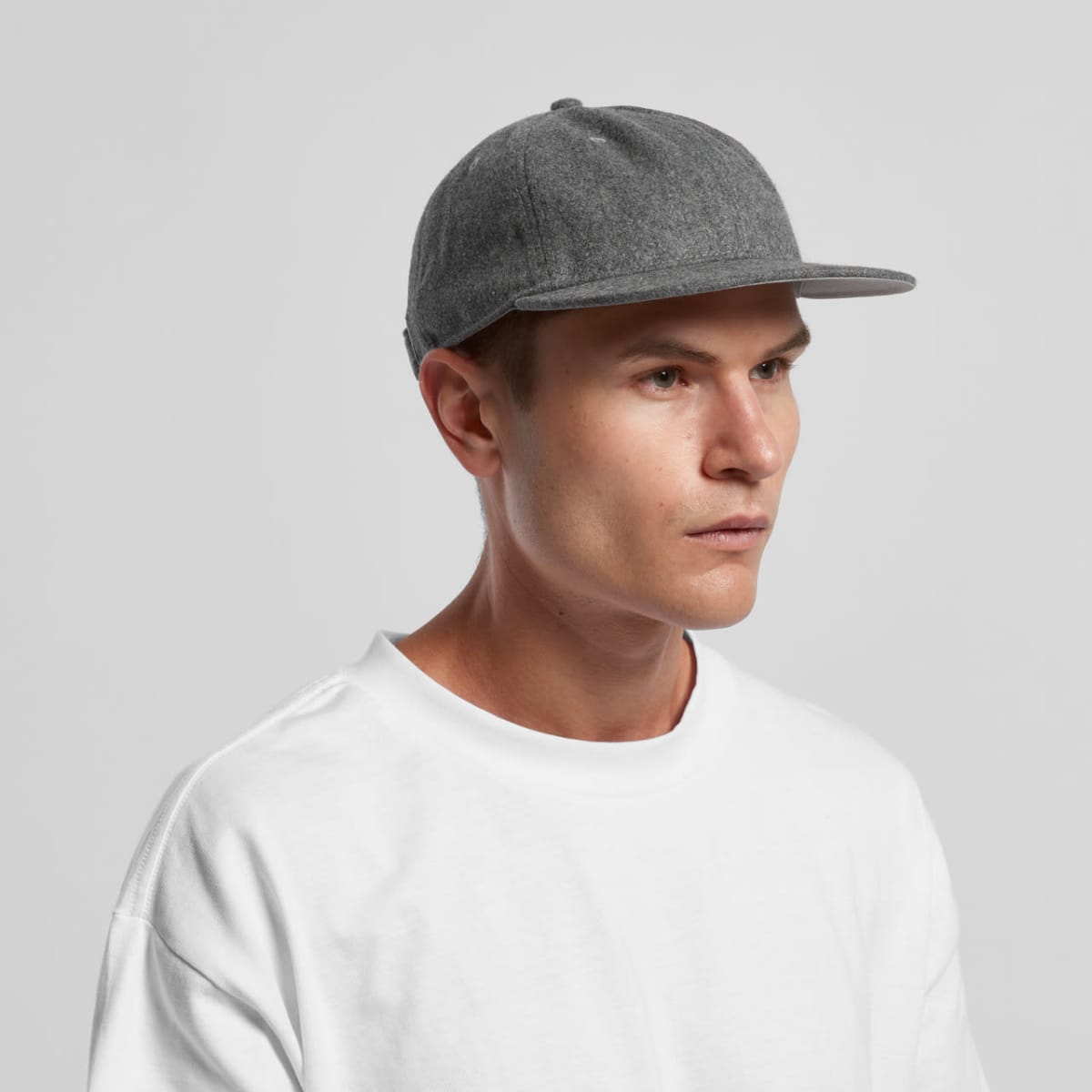 Person in a gray cap and white t-shirt looking to the side against a plain background.