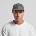 Man in a grey cap and white shirt looking straight at the camera against a plain background.