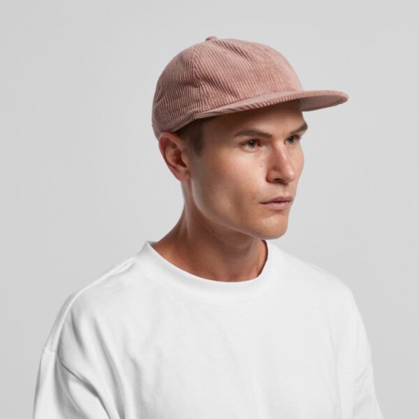 Man wearing a pink corduroy cap and a white shirt, looking to the side against a plain background.