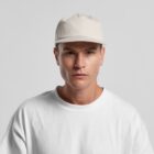 A man wearing a white cap and white t-shirt poses against a plain gray background.