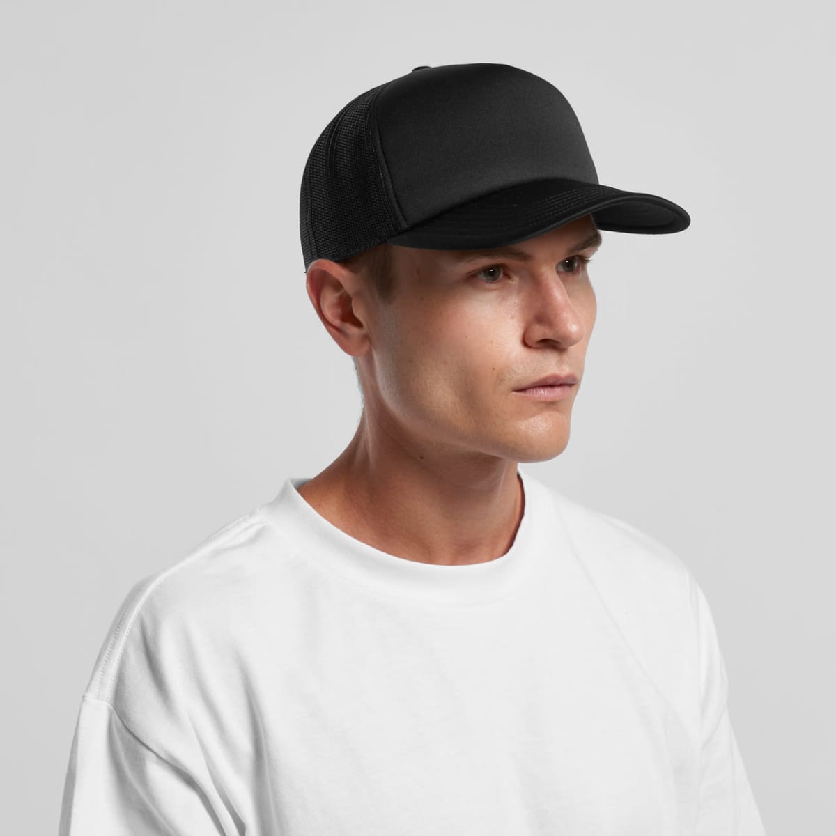 Man in a white shirt wearing a black baseball cap, looking off to the side.