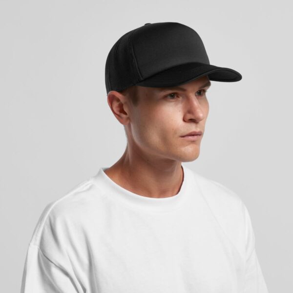 Man in a white t-shirt and black cap looking to the side against a plain background.