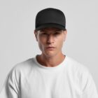 Man in white shirt and black baseball cap facing forward against a plain background.