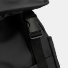 Close-up of a black buckle and strap on a dark gray backpack.