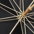 Close-up view of the inside of a black umbrella with a wooden handle and ribs.