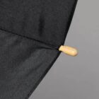 Close-up of a black umbrella tip with a wooden end against a gray background.