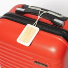 Red suitcase with a wooden luggage tag attached to the handle.