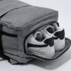 Gray backpack with a shoe compartment holding a pair of white sneakers.