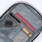 Open backpack showing organizer pockets with pens, a notebook, and a small case inside.