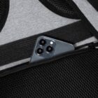 Smartphone with three cameras partially inside a black mesh pocket.