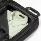 A light green shirt neatly packed inside a black suitcase.