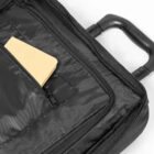 Black suitcase with a front zipper pocket containing a closed yellow notepad.