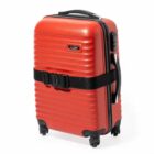 Red hard shell suitcase with wheels and a black strap.