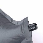 Close-up of a black fabric pillow with an inflation valve on a white background.