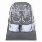 Gray drawstring bag with shoe design and visible white sneakers inside.