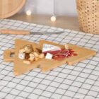 Tree-shaped wooden board with cheese, bread, and meat on a checkered cloth.