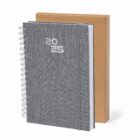 A gray 2025 spiral planner with an elastic band, next to a brown cardboard box.