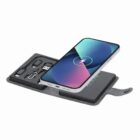 Smartphone charging wirelessly on a portable charging kit with multiple cable adapters.
