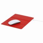 A white computer mouse on a red rectangular mouse pad with a charging cable attached.