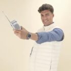 Smiling man holding a small portable radio with an extended antenna.