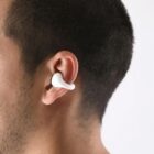 A person wearing a white wireless earbud in their right ear.
