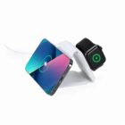 A phone and smart watch charging wirelessly on a white charging stand.