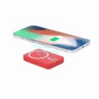 Smartphone wirelessly charging on a red charging pad, battery icon displayed on screen.