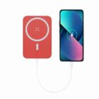 Red wireless charger connected by cable to a smartphone with a charging icon on the screen.
