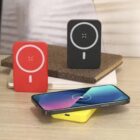 Three wireless chargers and a smartphone displayed on a desk with two notebooks in the background.