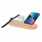 A wooden wireless charging pad with a phone, smartwatch, and earbuds on top.