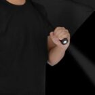 Person in a black shirt holding a black umbrella against a black background.