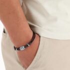 Person wearing a brown bracelet with hand in the pocket of beige pants.