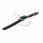 Smartwatch with black strap and metal clip on a white wireless charging pad.