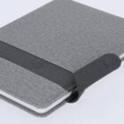 Grey fabric-covered notebook with an attached elastic strap securing it closed.