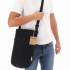 A person wearing a white shirt and jeans with a black crossbody bag.