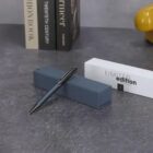 Pen on a gray box, with limited edition packaging and books in the background.