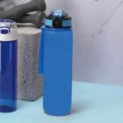 Two blue water bottles on a light blue surface, one with a strap and pop-up lid.