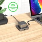 Charging station and laptop on a wooden desk with PD Fast Charge 100W text displayed.