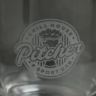 Etched logo reading Pitcher Grill House & Sport Bar on a glass surface.
