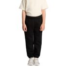 Child wearing a beige T-shirt, black pants, and white sneakers stands against a white background.