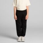 Child wearing a cream shirt, black pants, and white sneakers against a gray background.