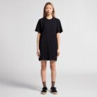 Person wearing a black T-shirt dress stands against a plain backdrop.