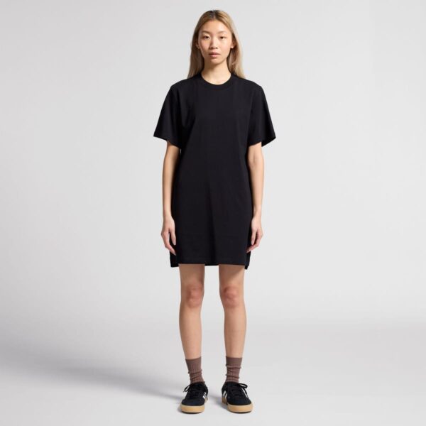 Person in a black t-shirt dress standing in a studio setting.