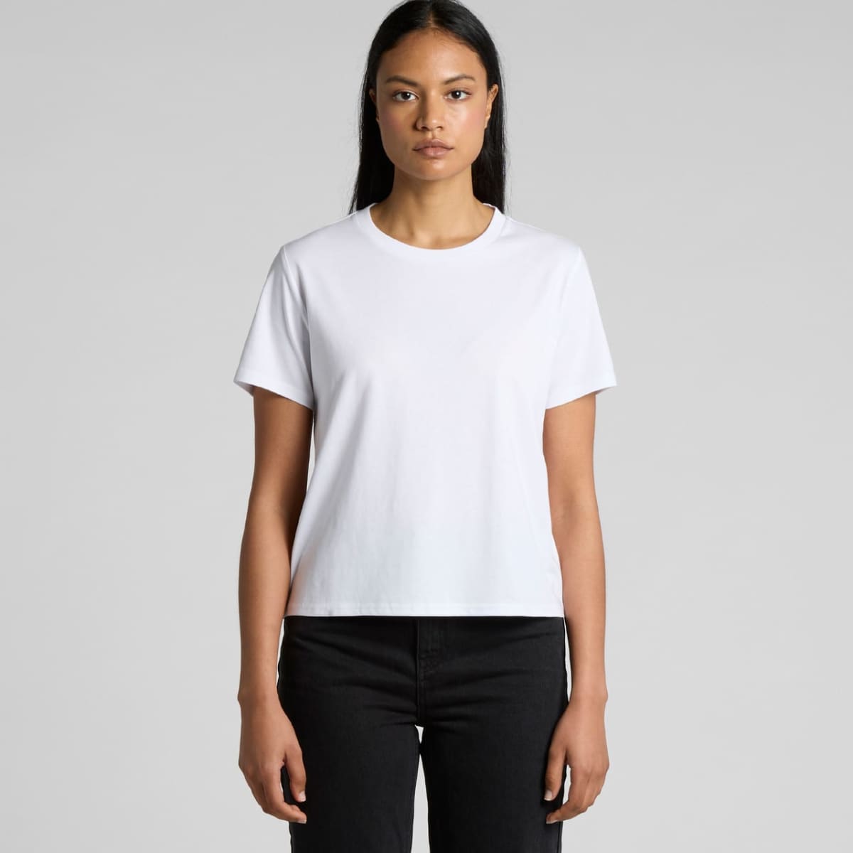 Woman in a plain white t-shirt and black pants standing against a light gray background.