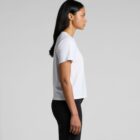 Woman in a white t-shirt and black jeans standing in profile against a plain background.