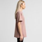 Person with long blonde hair in a mauve t-shirt standing in profile against a plain background.